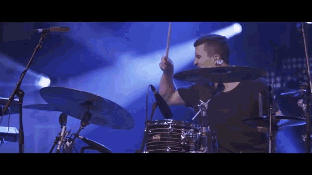 a man in a black shirt is playing drums