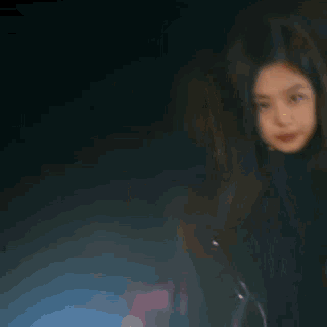 a blurry picture of a woman in a black jacket in the dark .