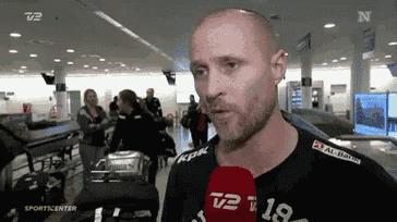 a man wearing a black shirt with the number 18 on it talks into a microphone