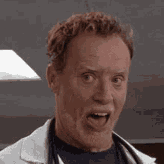 a close up of a man in a lab coat making a funny face with his eyes closed .
