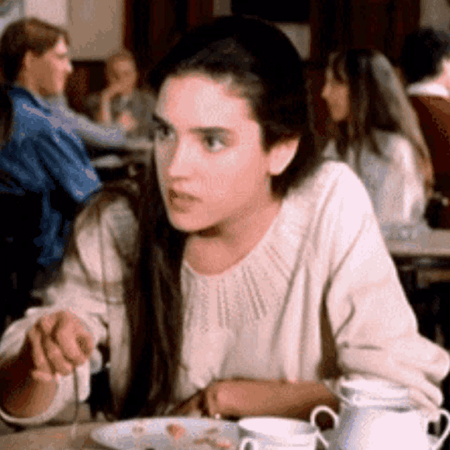 a woman is sitting at a table eating food with a fork and knife .