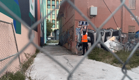 a man in an orange vest is standing in an alleyway with graffiti on the walls