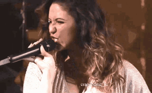 a woman singing into a microphone with crapmantic_be written below her