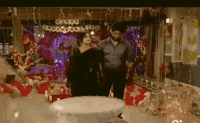 a man and a woman are standing in a room decorated for a birthday party .