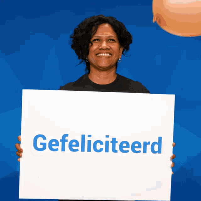 a woman holds a sign that says gefeliciteerd