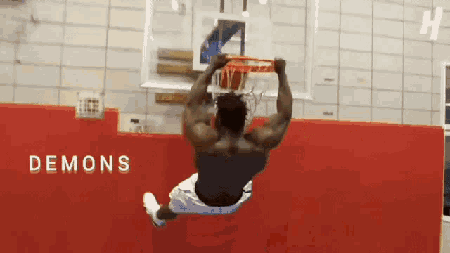 a basketball player is jumping over a basketball hoop with the words demons behind him