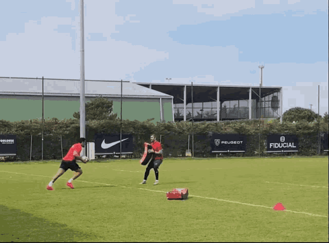 two soccer players on a field with a peugeot sign