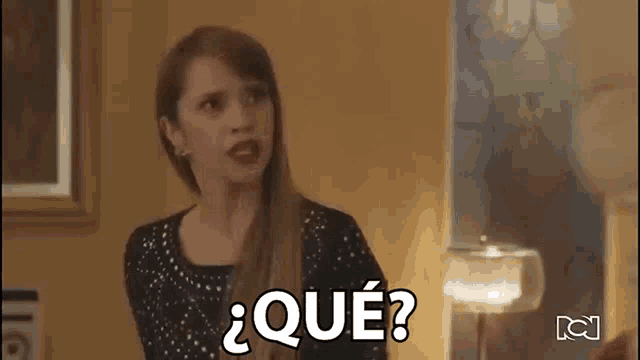 a woman in a black dress is making a funny face and saying `` qué '' .