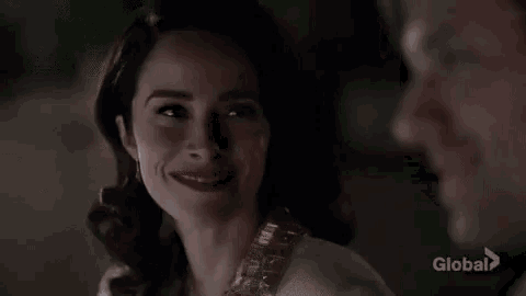 a man in a white shirt and black tie is smiling while looking at another man .