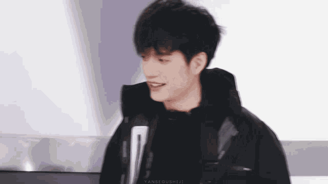 a young man wearing a black jacket and a black shirt is smiling .