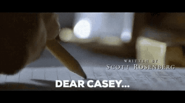 a close up of a person writing on a piece of paper with the words dear casey