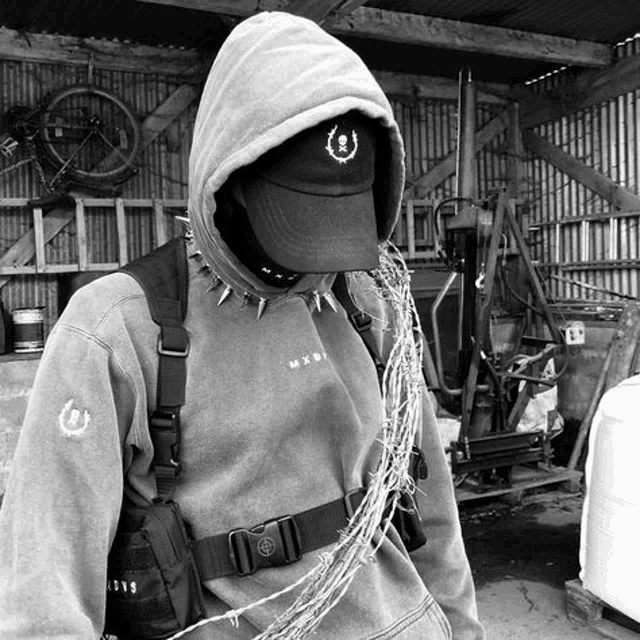a black and white photo of a person wearing a hoodie and a hat with barbed wire .