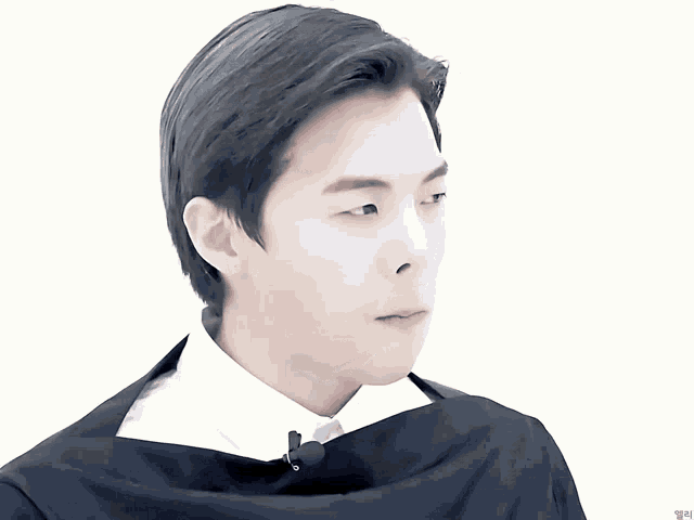 a close up of a man 's face with a white shirt and black cape