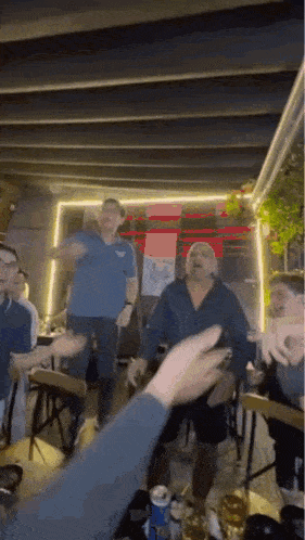 a group of people are sitting at a table in a restaurant dancing .