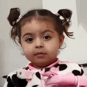 a little girl is making a funny face while wearing a cow pajama .