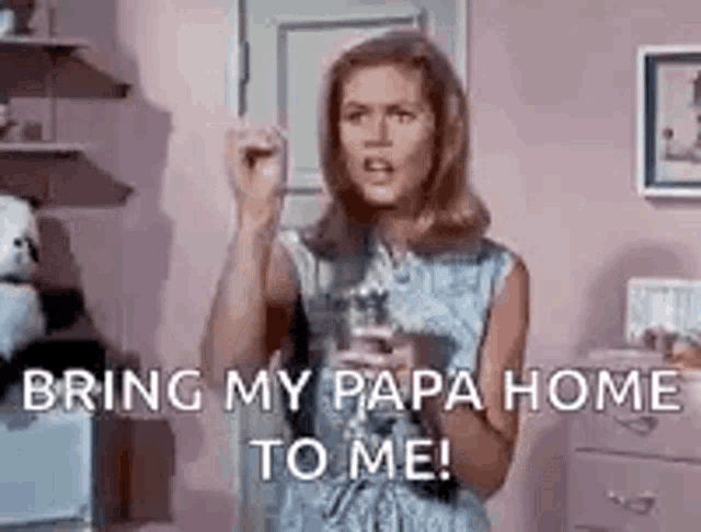a woman is standing in a pink room holding a glass of water and yelling .