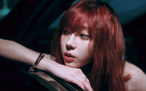 a woman with red hair is sitting in a car with her hand on the window .