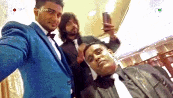 a man in a blue suit is taking a selfie with his friends