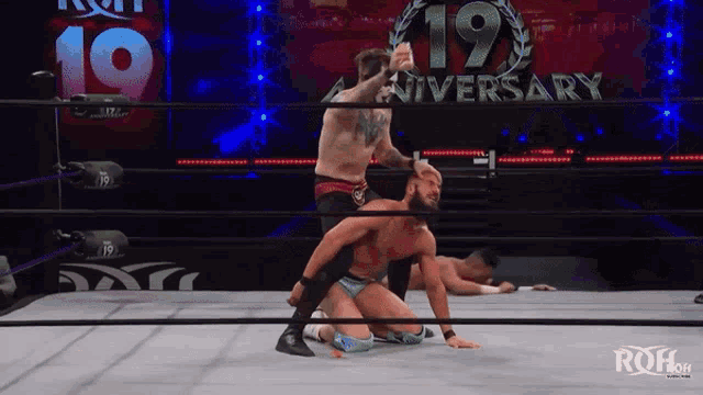 a wrestler in a ring with a 19th anniversary sign behind him