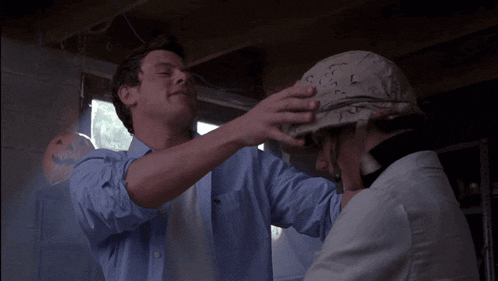 a man wearing a helmet with the letter l on it talks to another man