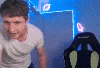 a man in a white shirt is standing in front of a gaming chair