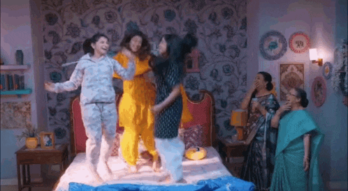 a group of women are jumping on a bed in a room .