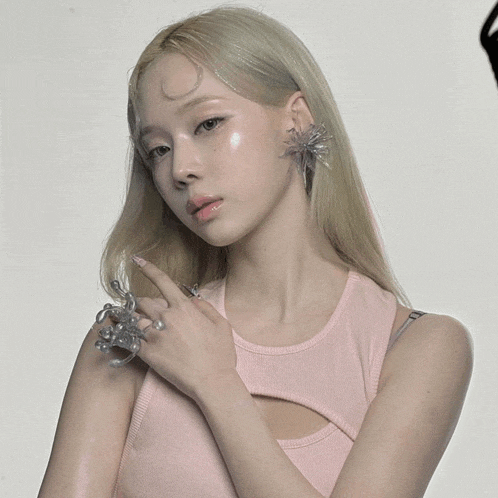 a woman wearing a pink tank top and a clear ring on her finger