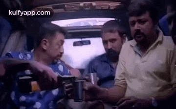 a group of men are sitting in a car drinking coffee and talking to each other .