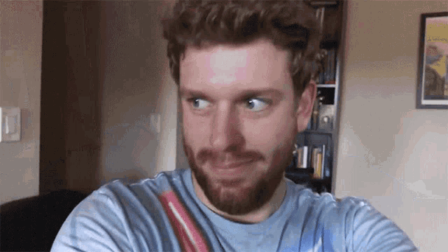 a man with a beard wearing a tie dye shirt is looking at the camera