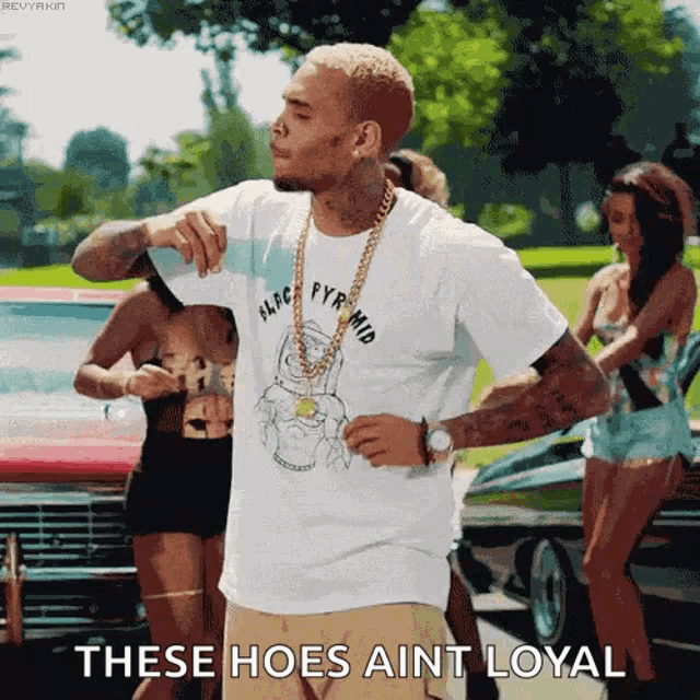 a man wearing a white t-shirt that says these hoes ain 't loyal on it