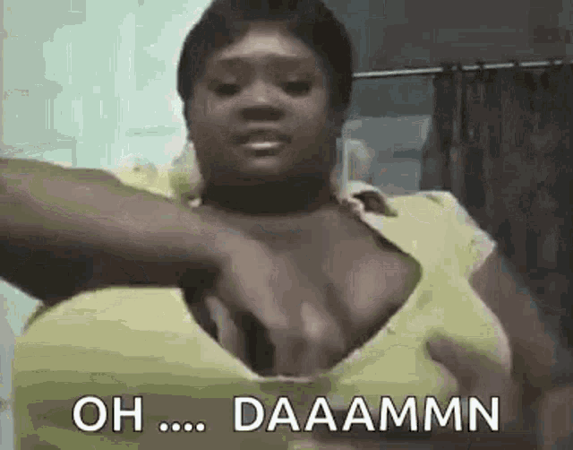 a woman in a yellow shirt is holding her breasts in a bathroom .