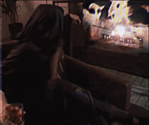 a woman is sitting in front of a fireplace with flames coming out
