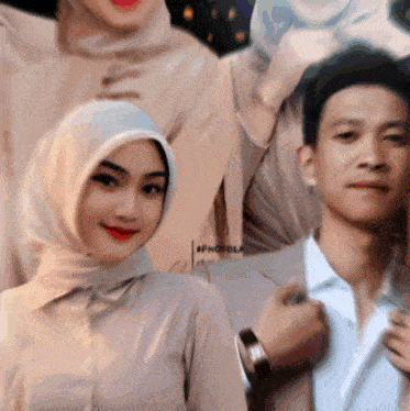 a woman wearing a hijab and a man in a suit pose for a photo