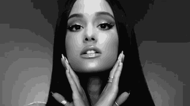 ariana grande is a black and white photo of a woman touching her face with her hands .