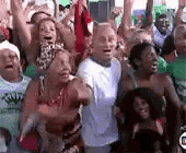 a crowd of people are standing in a room with their arms in the air .