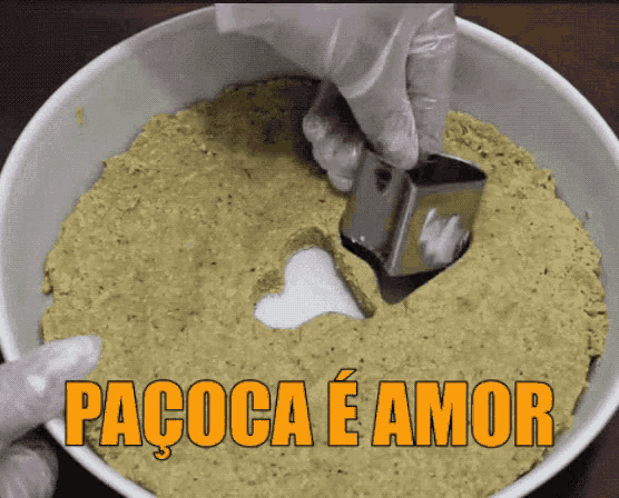 a person is making a heart shaped hole in a bowl with the words pacoca e amor written on the bottom