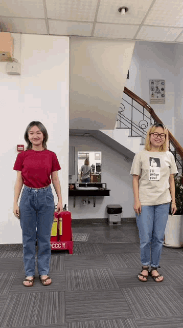 two women standing next to each other in front of a fire extinguisher that says ccc