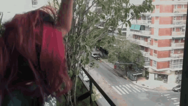 a woman with red hair stands on a balcony overlooking a city
