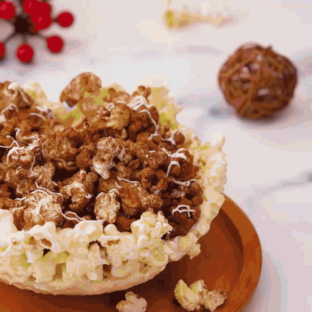 a bowl of popcorn with icing on top sits on a wooden plate