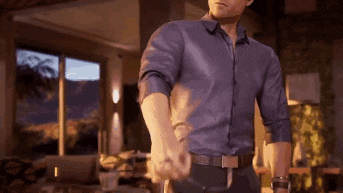 a man in a blue shirt and black pants is holding another man 's hand .