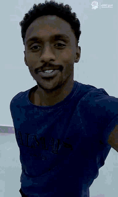 a man in a blue shirt is smiling and waving
