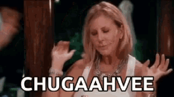 a woman in a white tank top is dancing with her hands in the air and the words chugaahvee are written on the screen .