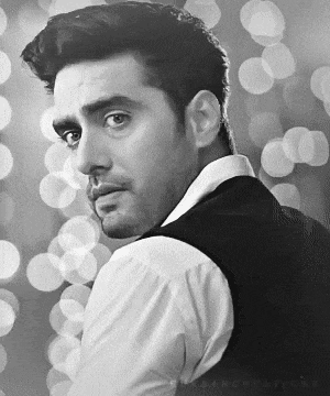 a man in a white shirt and black vest is looking over his shoulder in a black and white photo