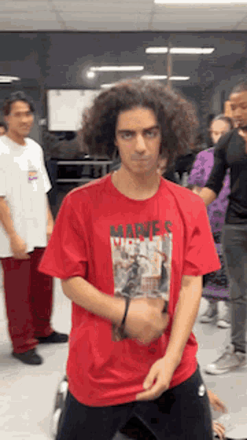 a man with curly hair wearing a red shirt that says madres