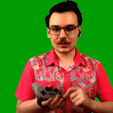 a man in a pink shirt and glasses is holding a video game controller .