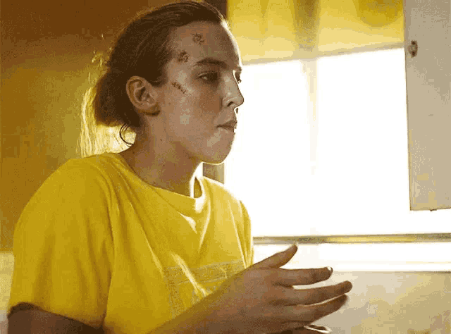 a woman in a yellow shirt has a few spots on her forehead