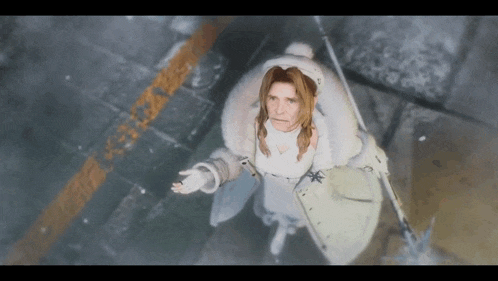 a woman in a white coat is standing on a sidewalk in the snow .