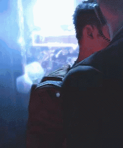 a man with a tattoo on his neck is looking out a window ..
