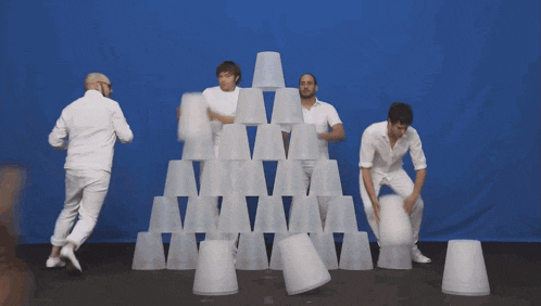 a group of men and a dog are dancing in front of a blue backdrop