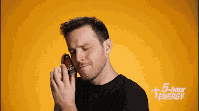 a man is holding a bottle of energy drink in front of a 5 hour energy sign